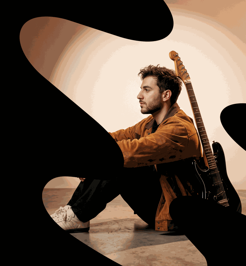 Artist seated on the floor with an electric guitar, framed by organic dark shapes